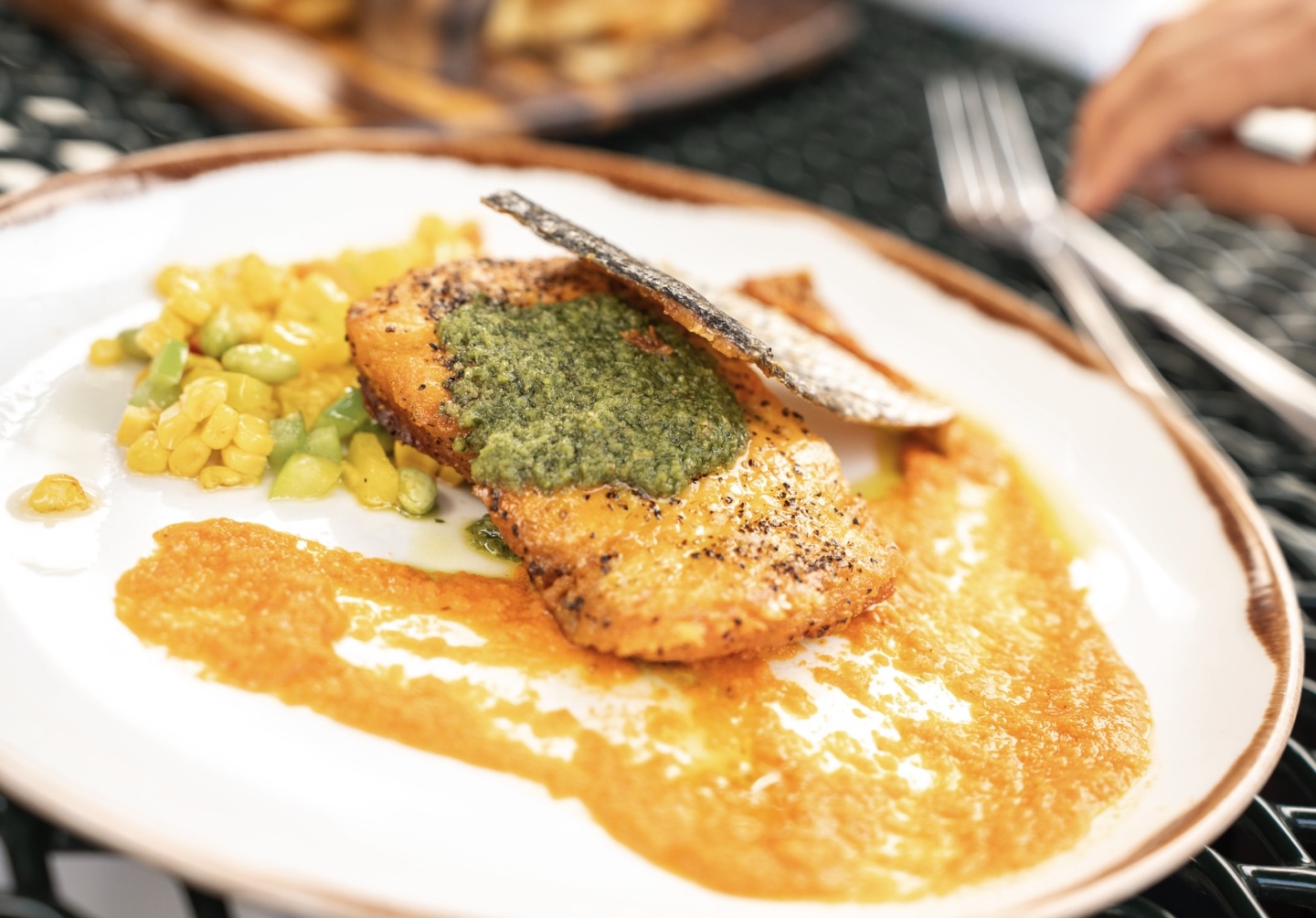 Grilled fish with pesto and sauce, served with vegetables on a white plate. 2