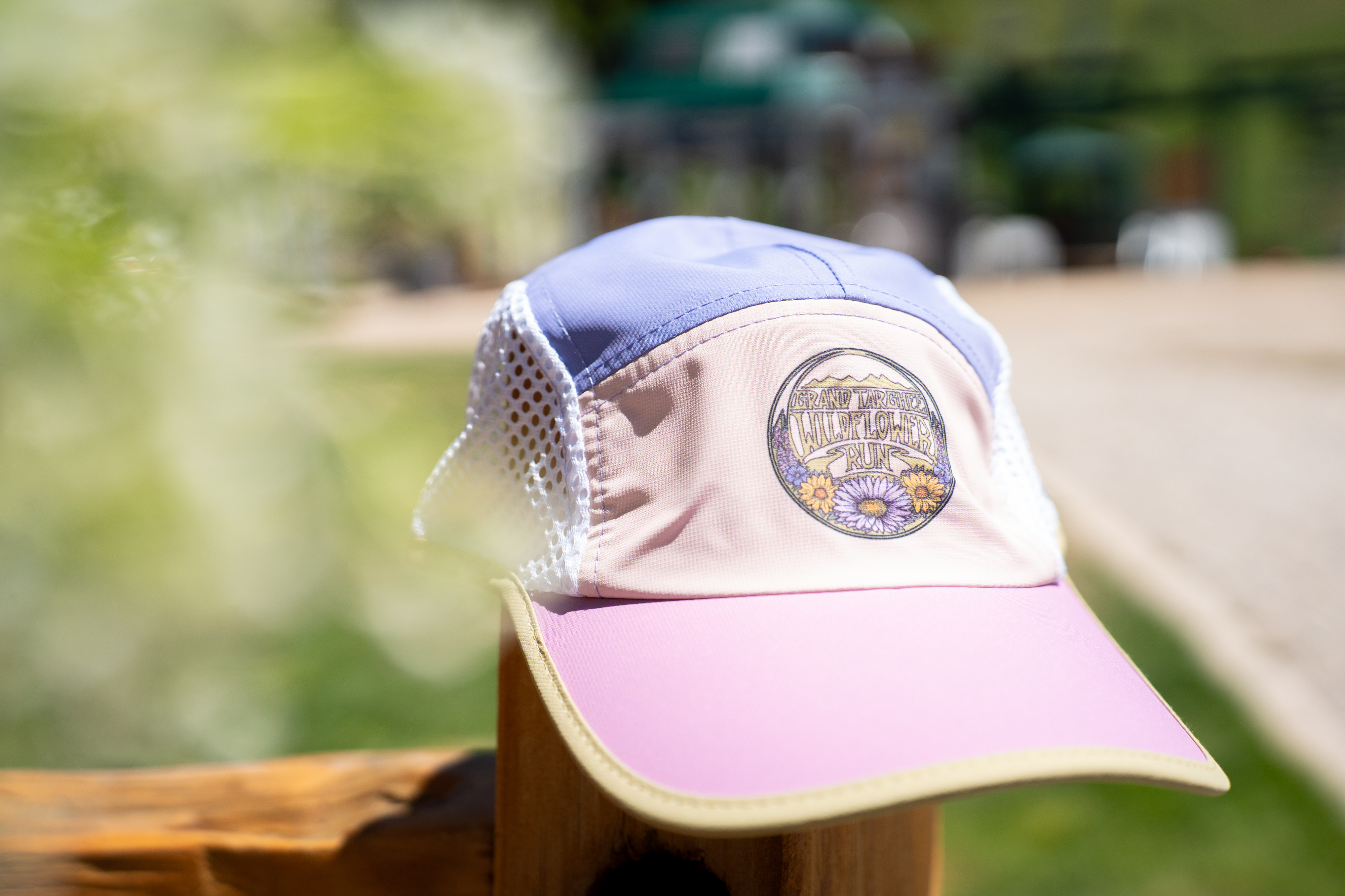 Trucker cap with pastel colors on a wooden fence outdoors.