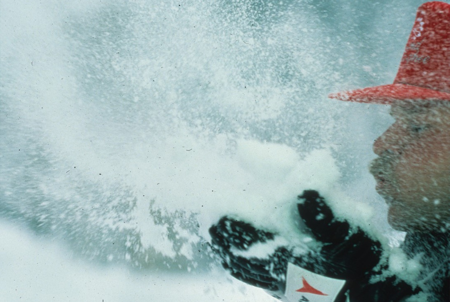 A man blows snow from his gloves