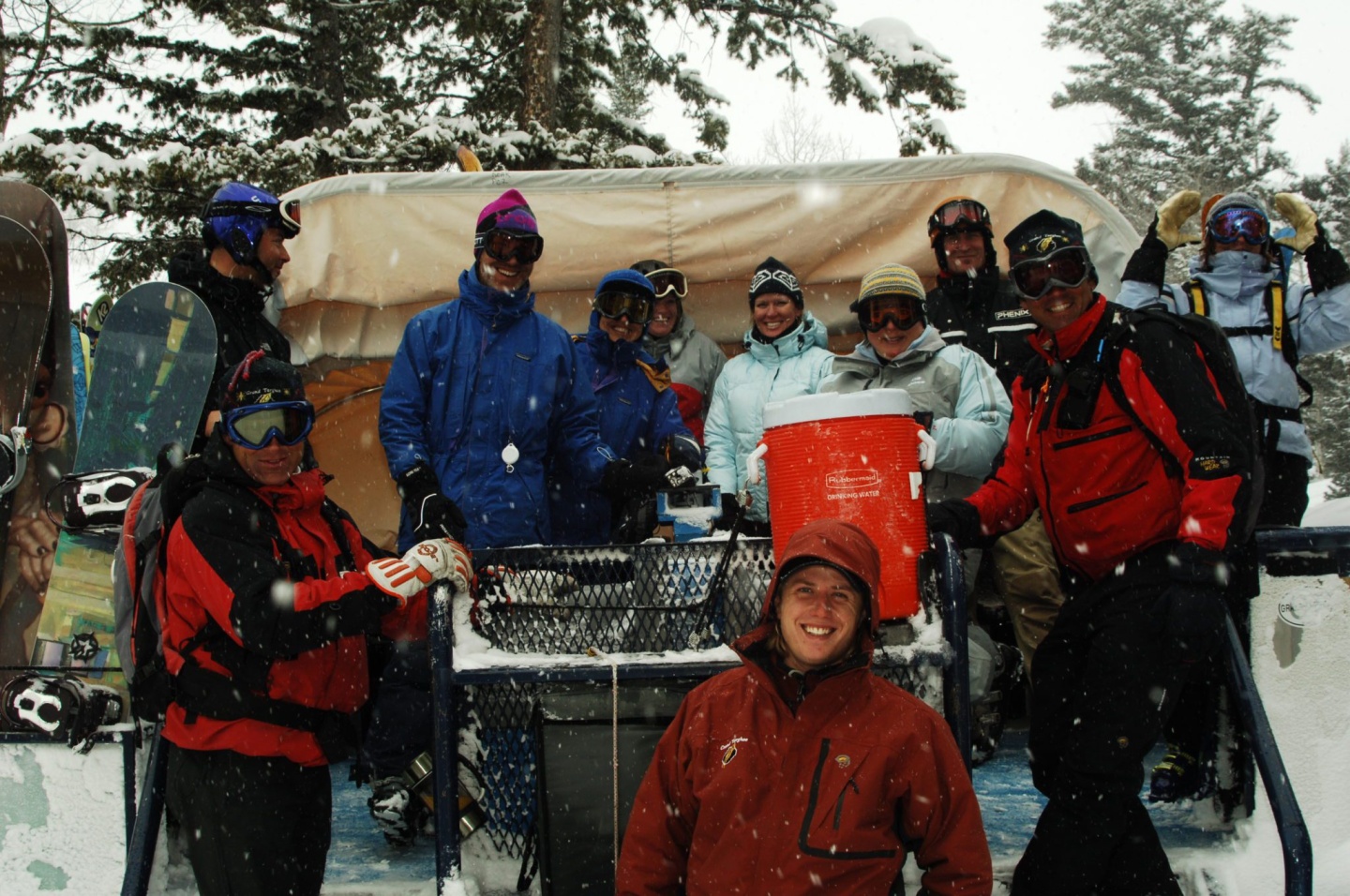 A group of cat skiers pose outside a tent in winter