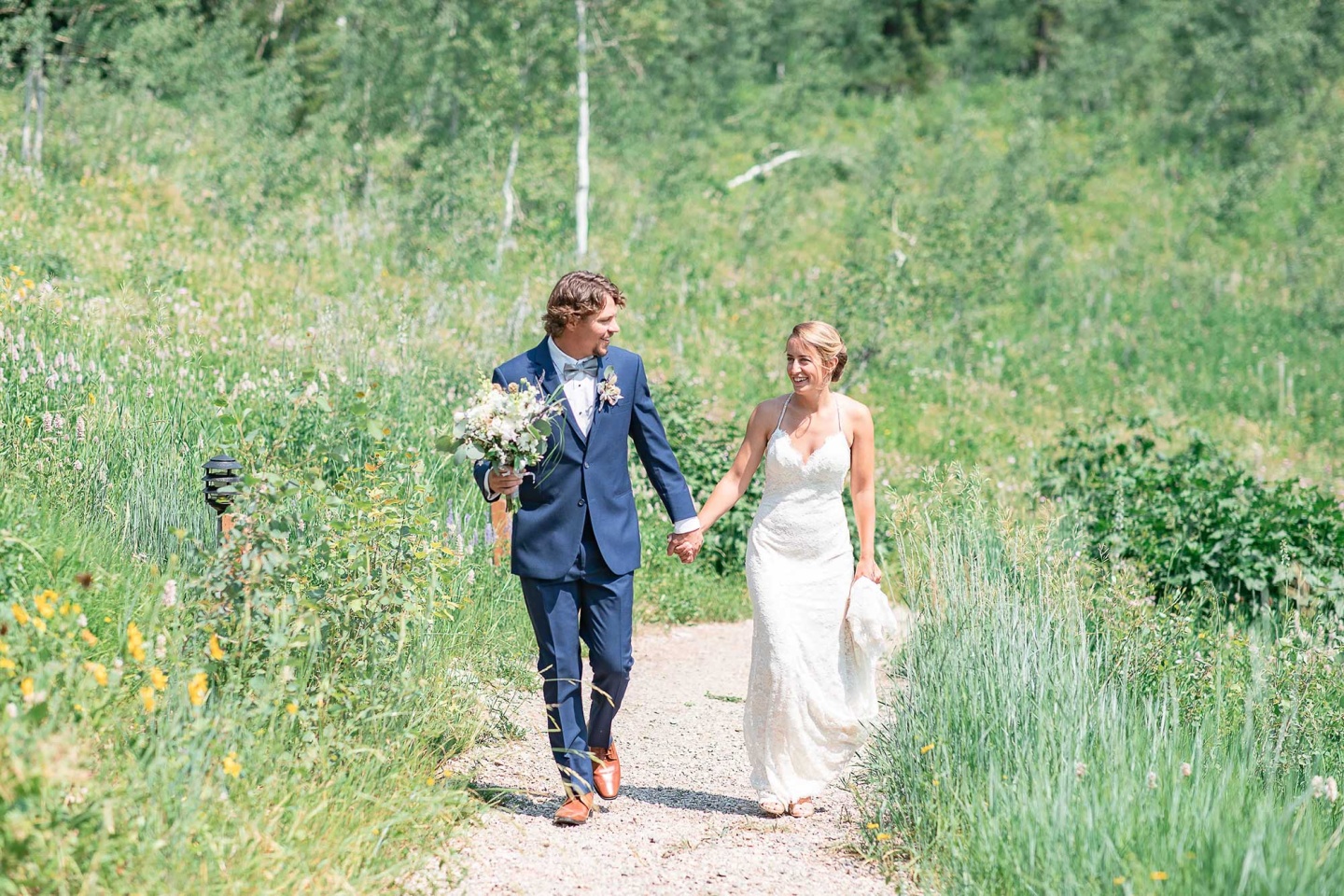 Wedding couple walking through grass