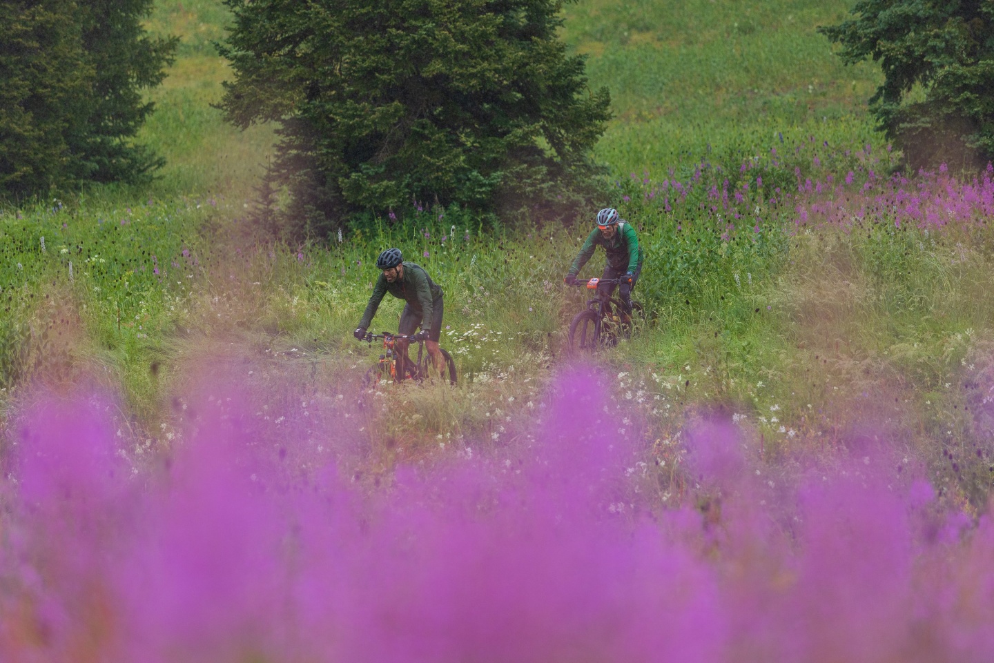 Two men cycling along a trail in the rain