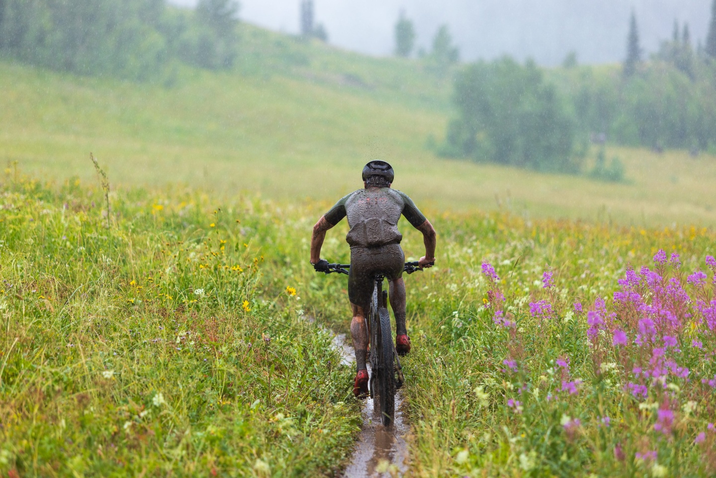 A man cycling along a trail in the rain