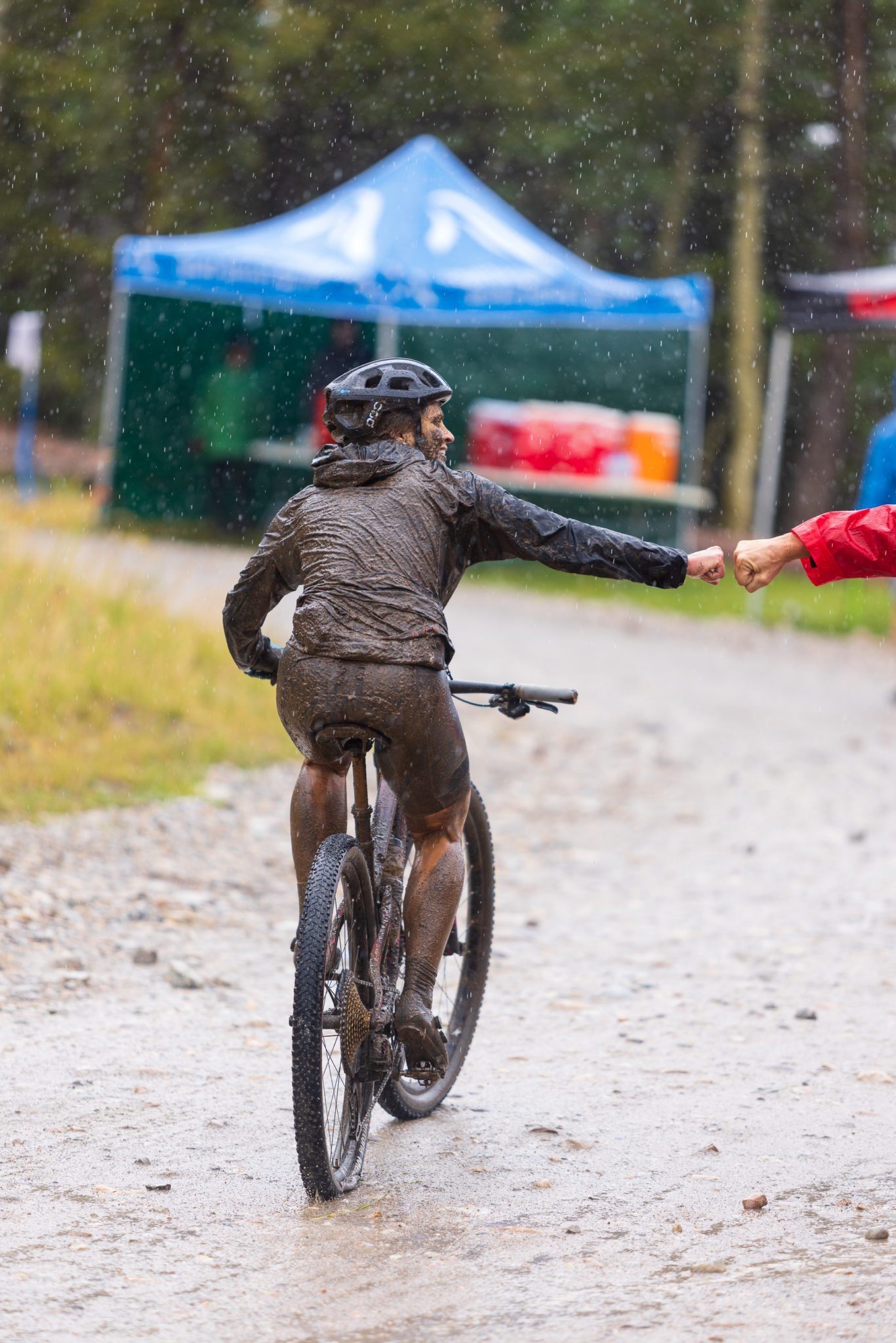 Two cyclists fist bumping in the rain
