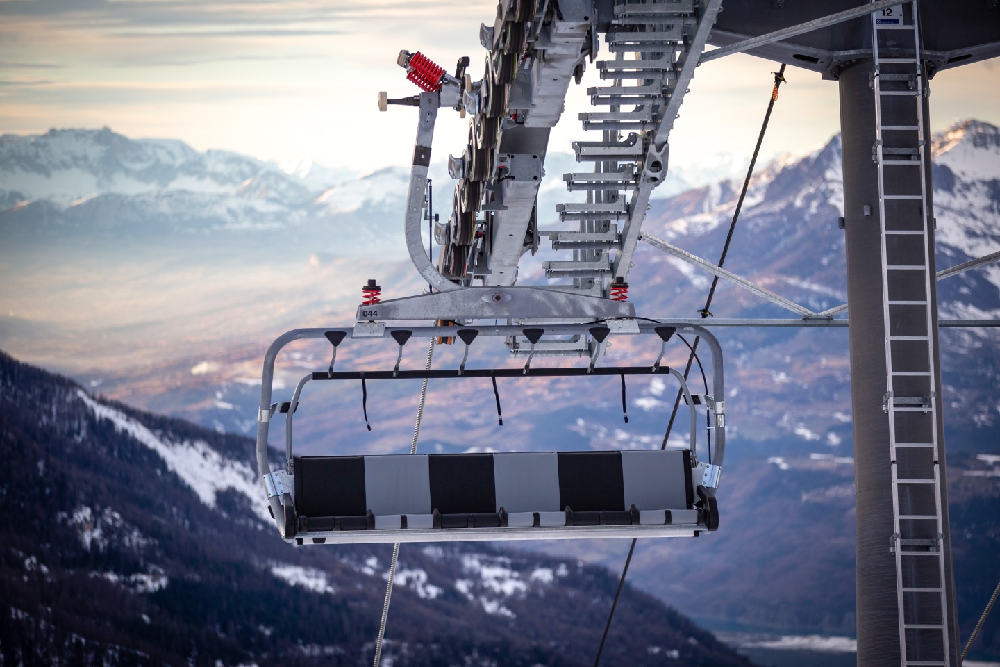 An empty chairlift with mountain views in the background