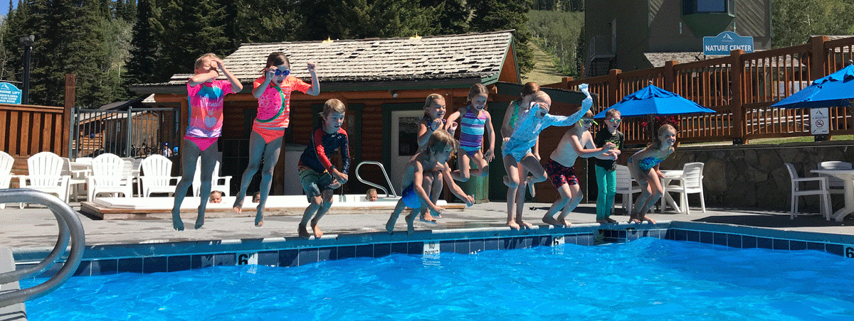 A group of kids jumping into a pool