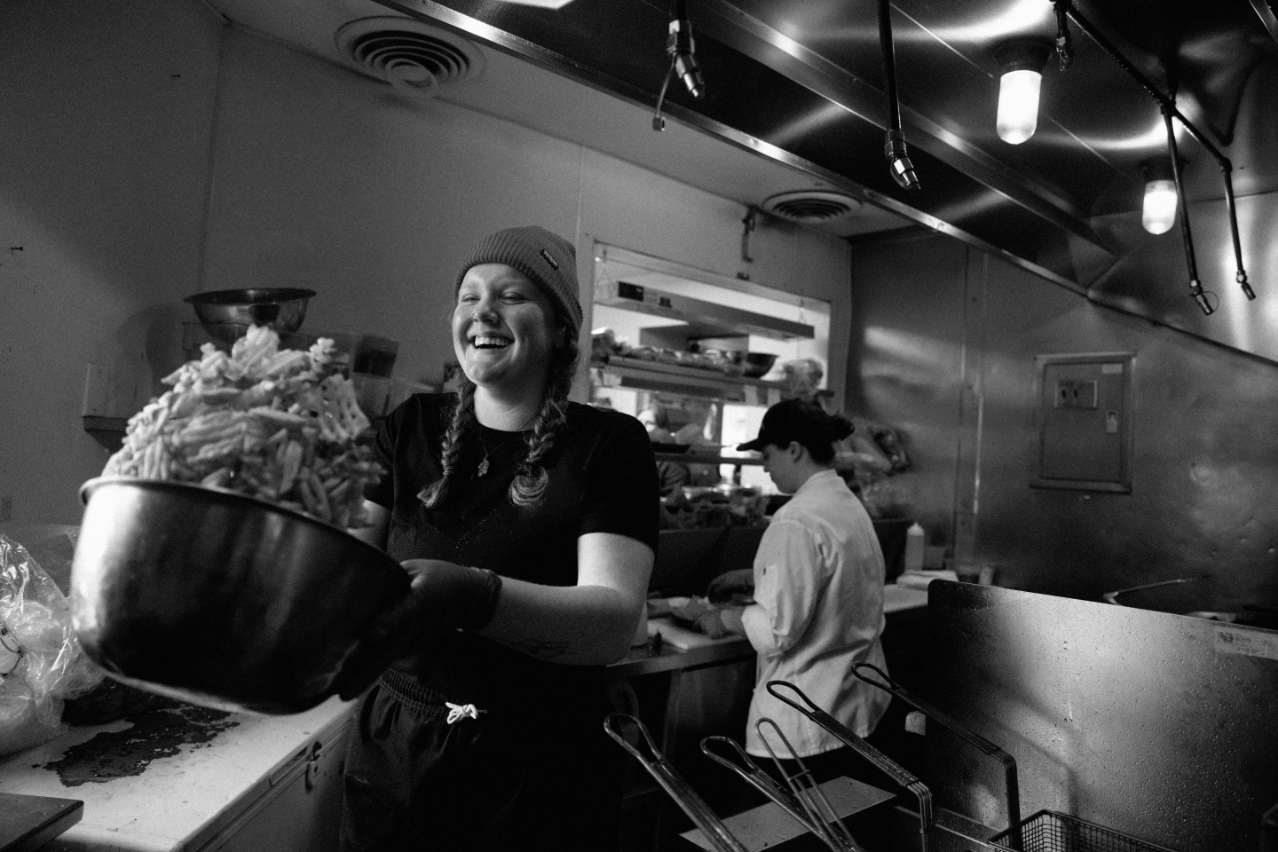A restaurant chef tosses a bowl of fries