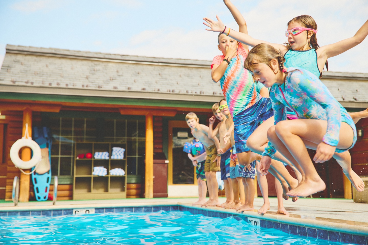 A group of kids jumping into a pool