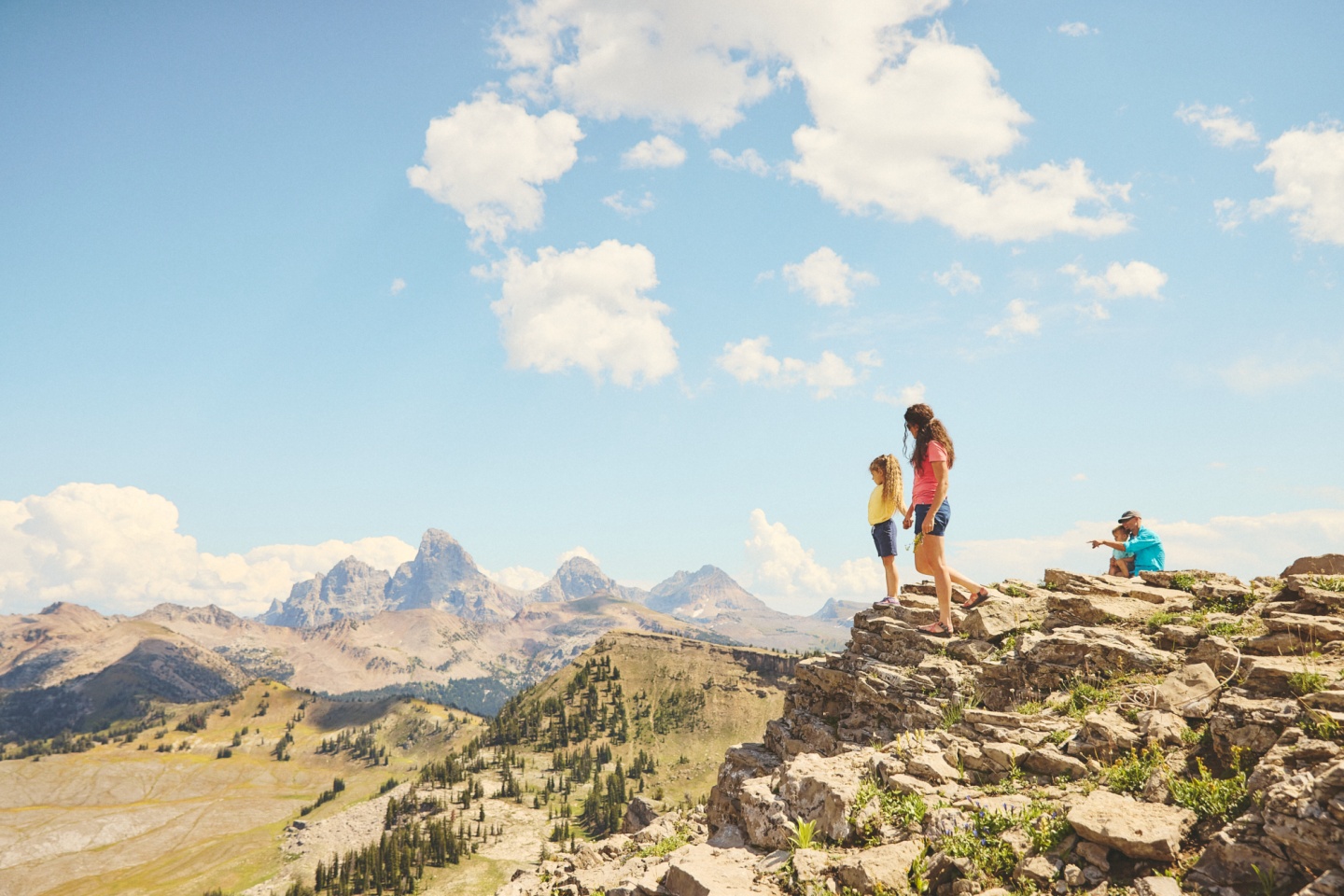 A family on top of a mountain looking out at the Tetons