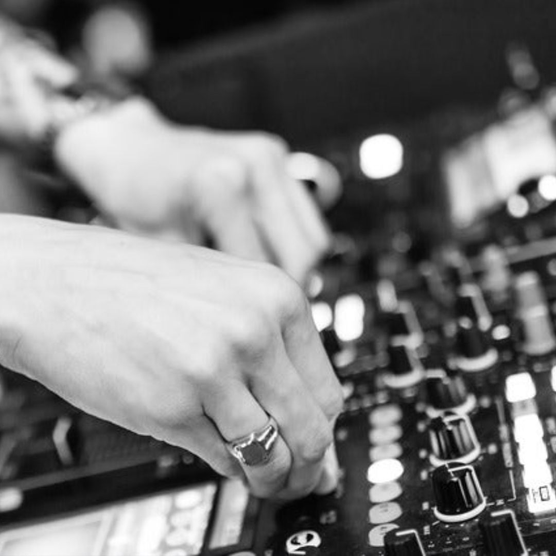 Hands adjusting a DJ mixer in black and white.