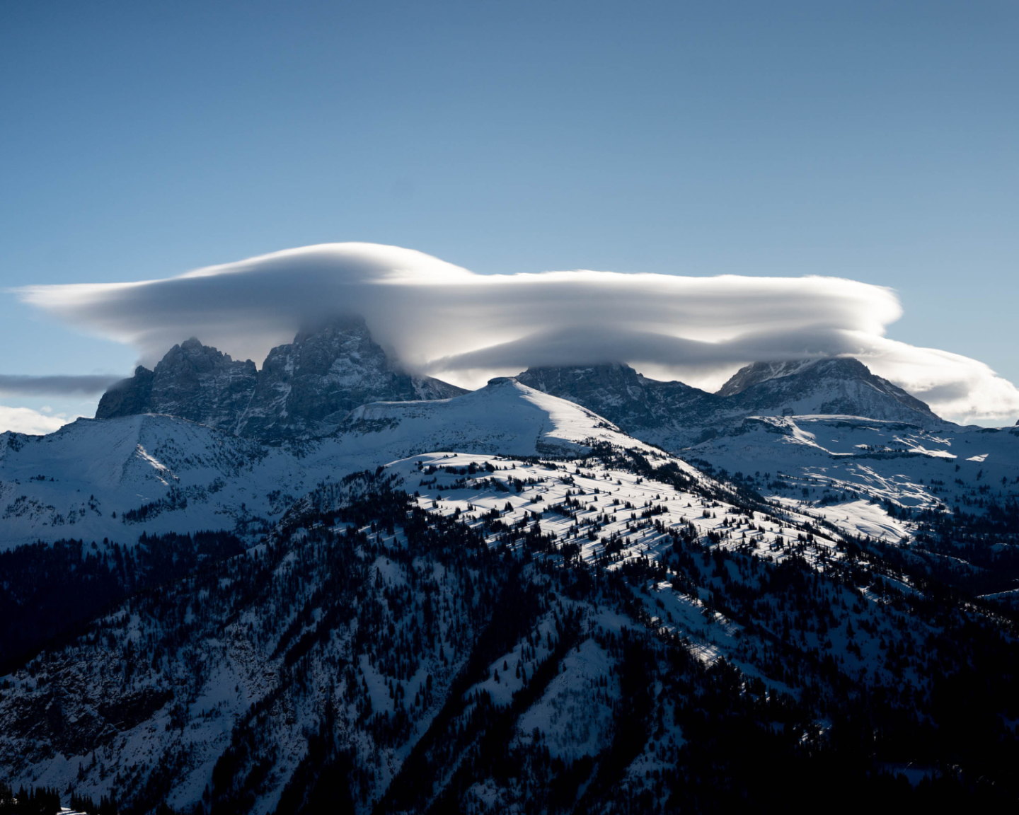 Snowy mountains under a smooth, cloud-capped sky.