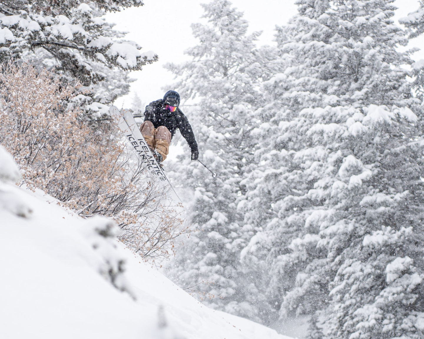 Snowboarder jumping through a snowy forest.