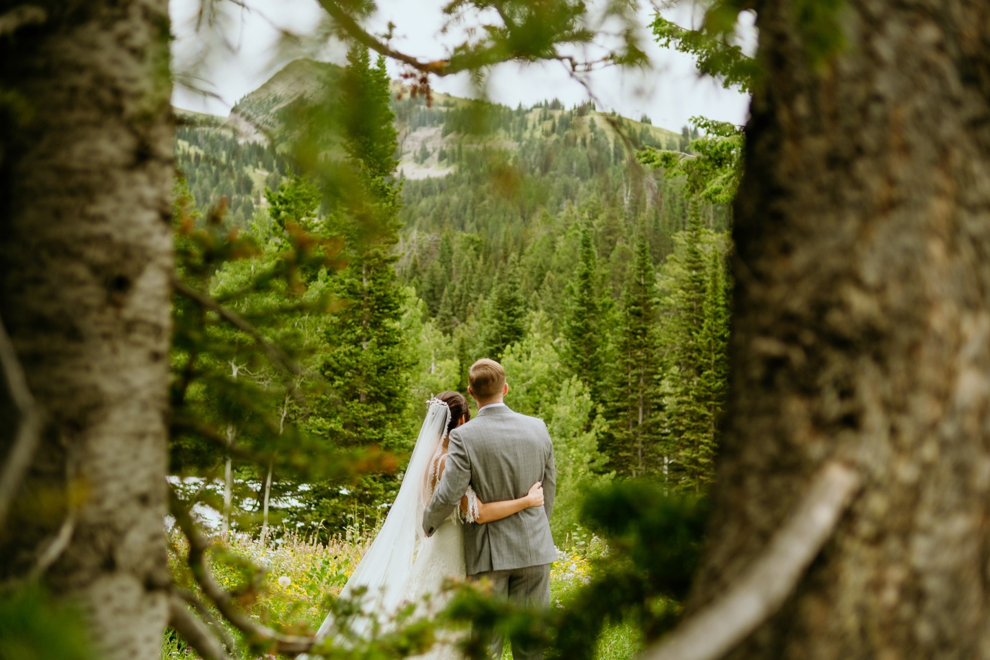 Bride and groom embracing in a lush forest clearing.