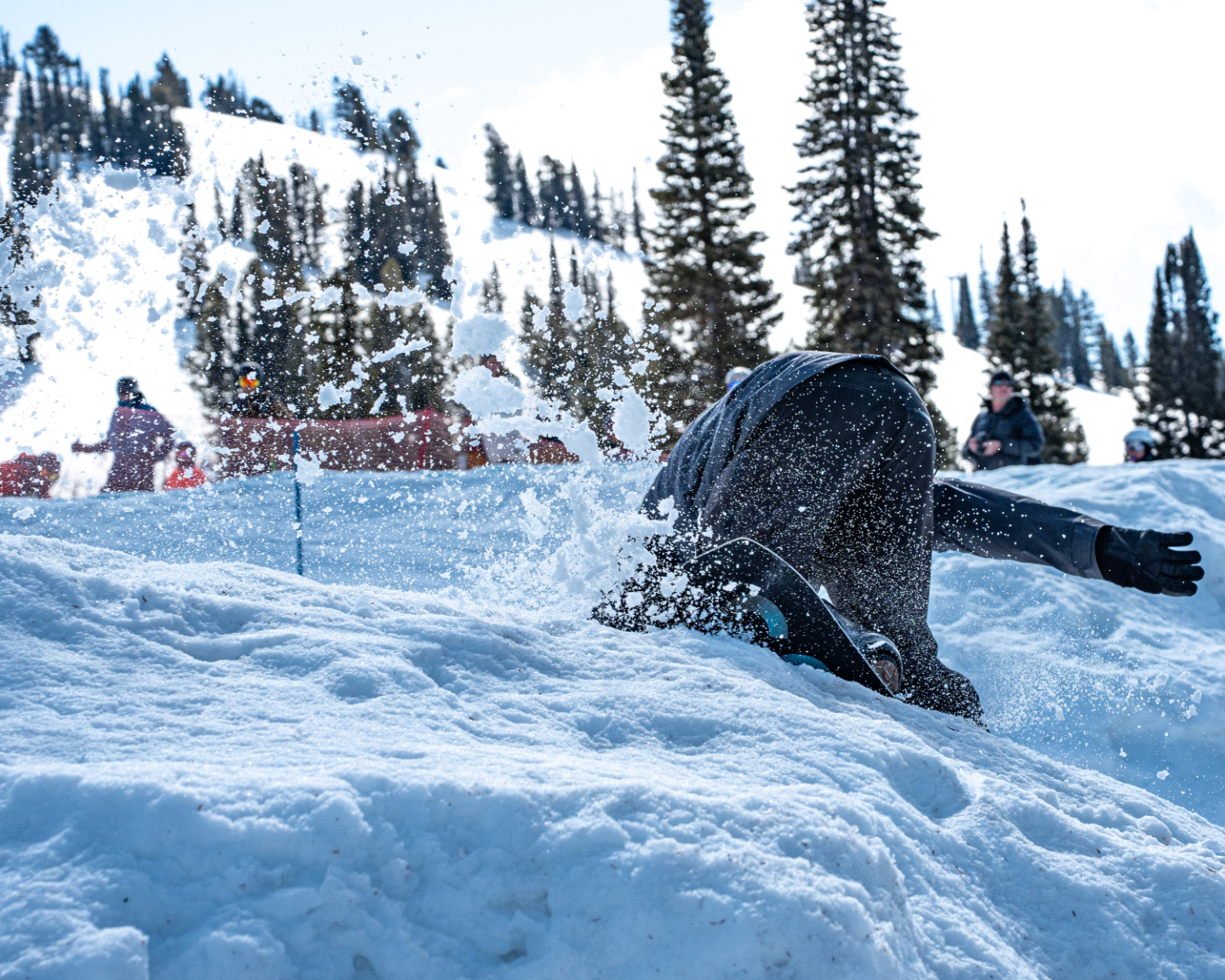 Person falling in snowy landscape with trees in the background.