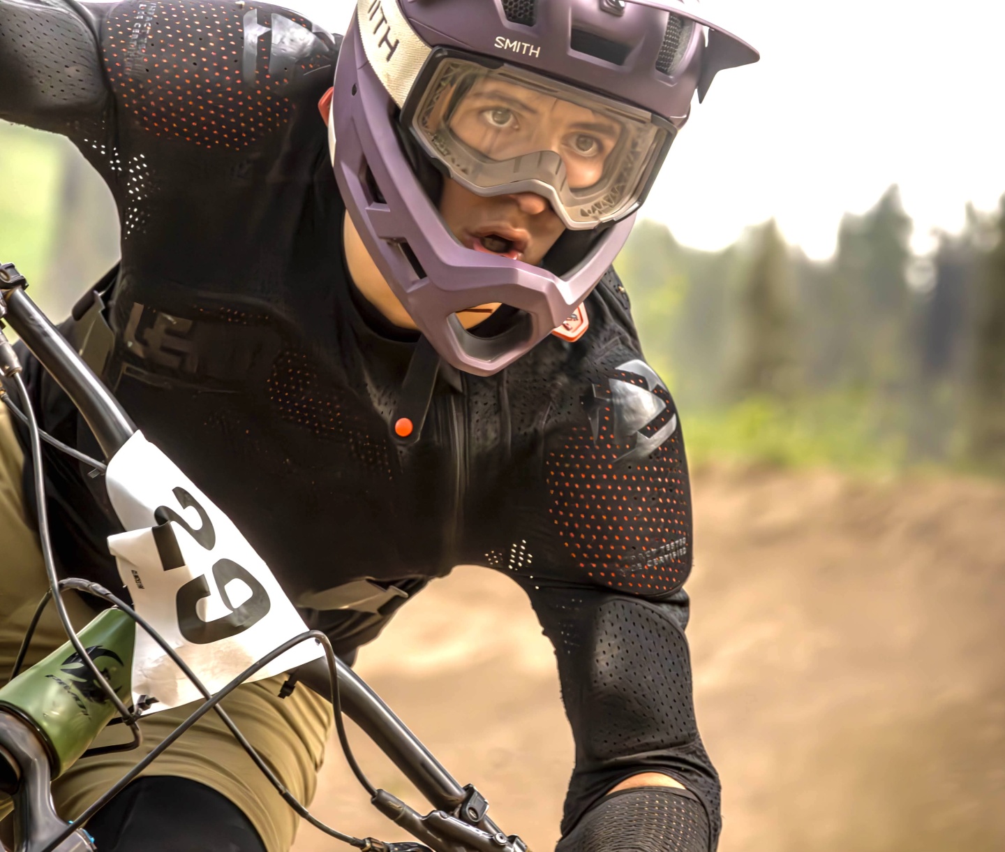 Mountain biker wearing a helmet and gear, racing on a dirt track.