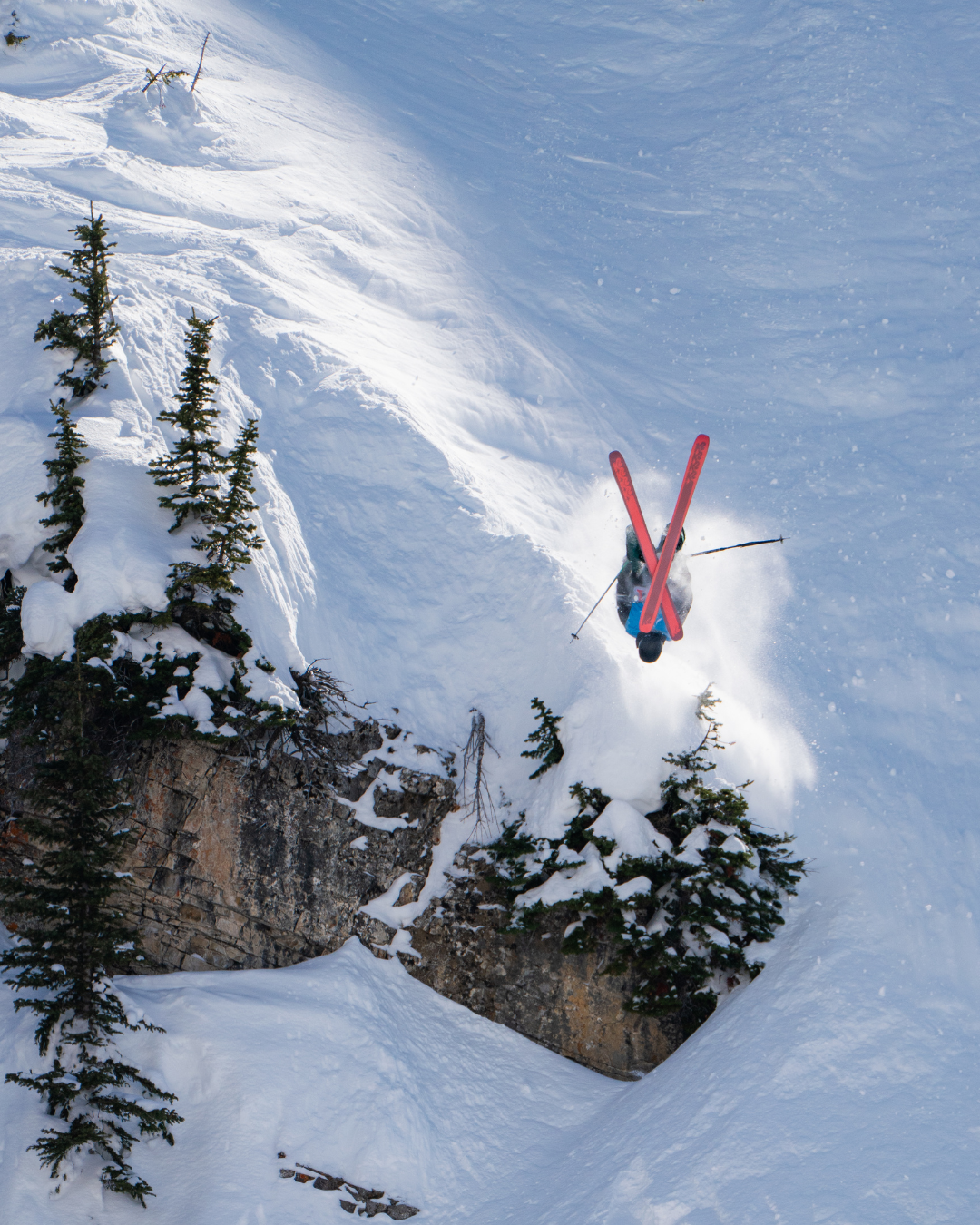 Skier in mid-air after jumping off a snowy cliff.