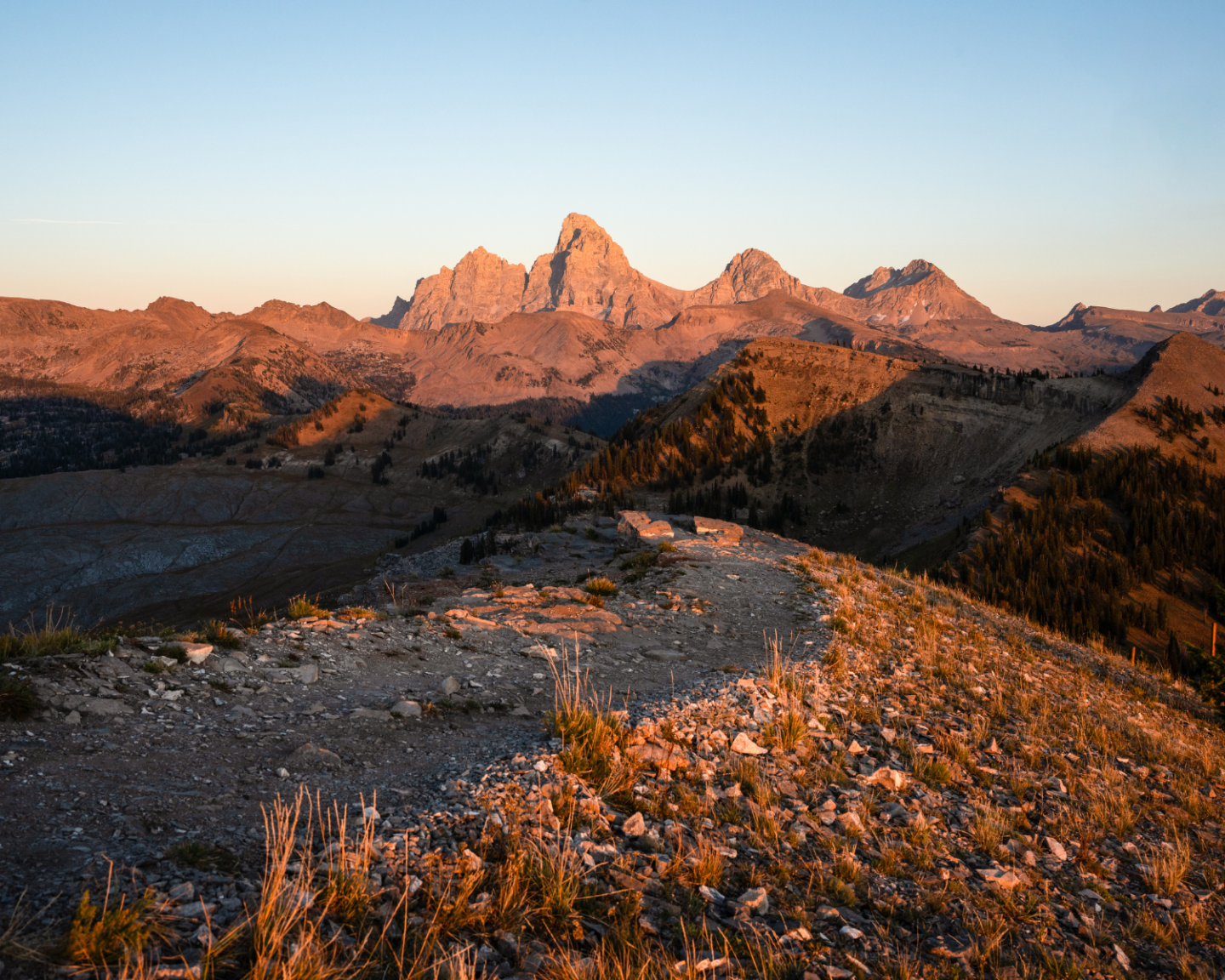 Mountain landscape at sunset with rocky foreground.