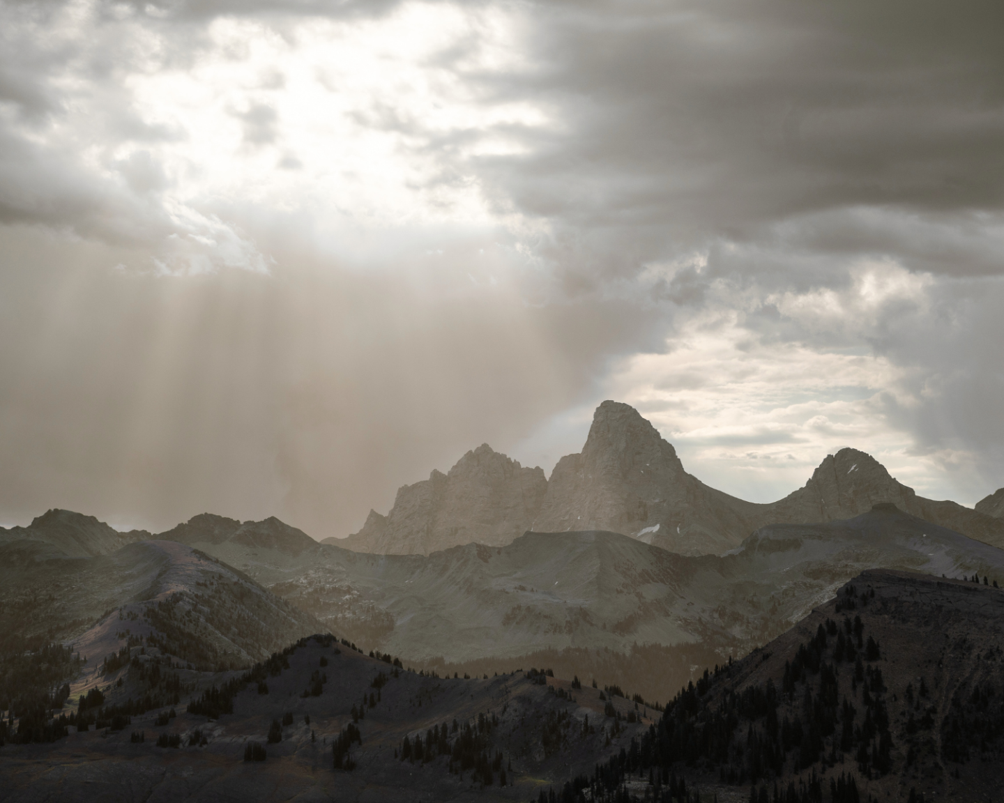 Sunrays breaking through clouds over rugged mountain peaks.