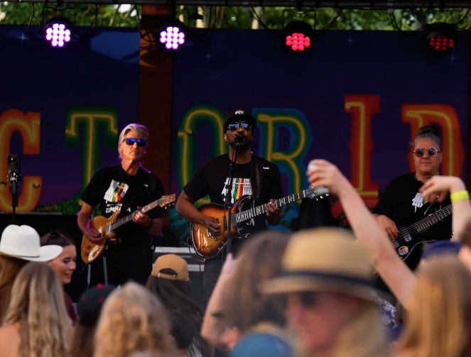 Band performing on stage with guitars, crowd enjoying the music.