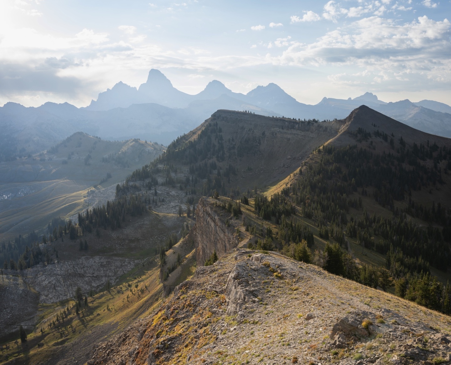 Mountain ridge with trees under a cloudy sky.
