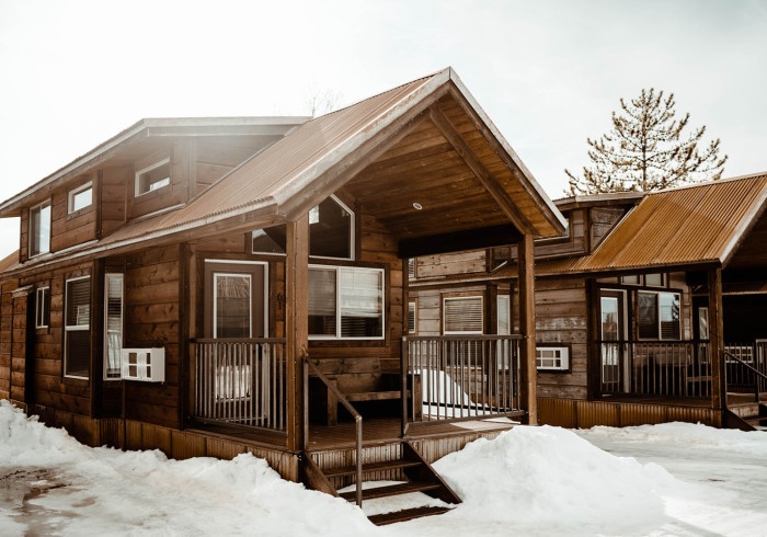 Two wooden cabins in a snowy landscape under a clear sky.