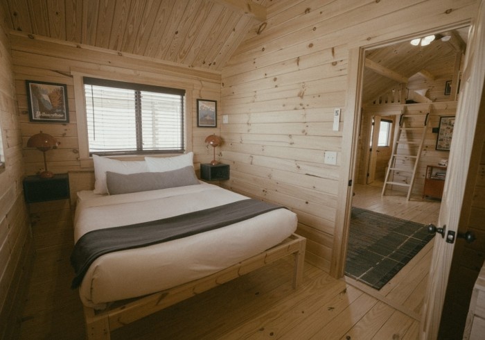 Cozy wooden cabin bedroom with a large bed and soft lighting.