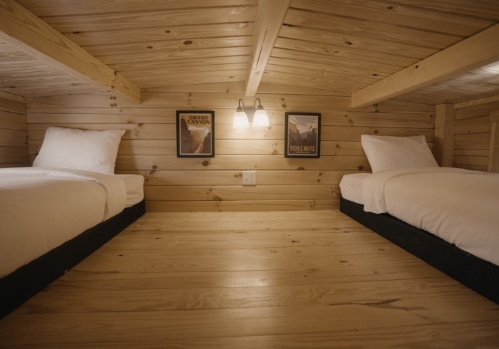 Cozy wooden attic room with two single beds and framed photos.