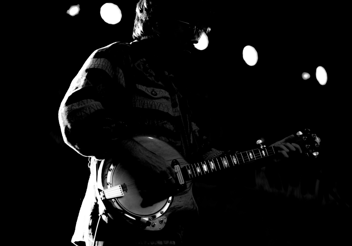 Silhouette of a guitarist playing on stage with bright stage lights.