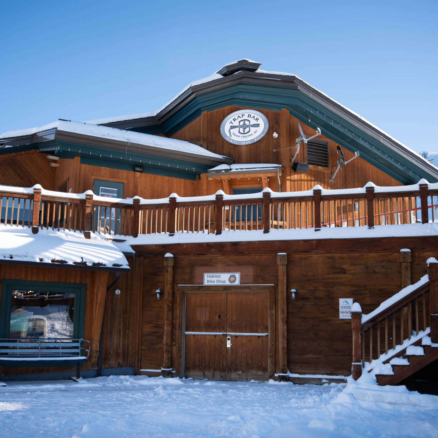 Wooden cabin in snowy landscape with blue sky.