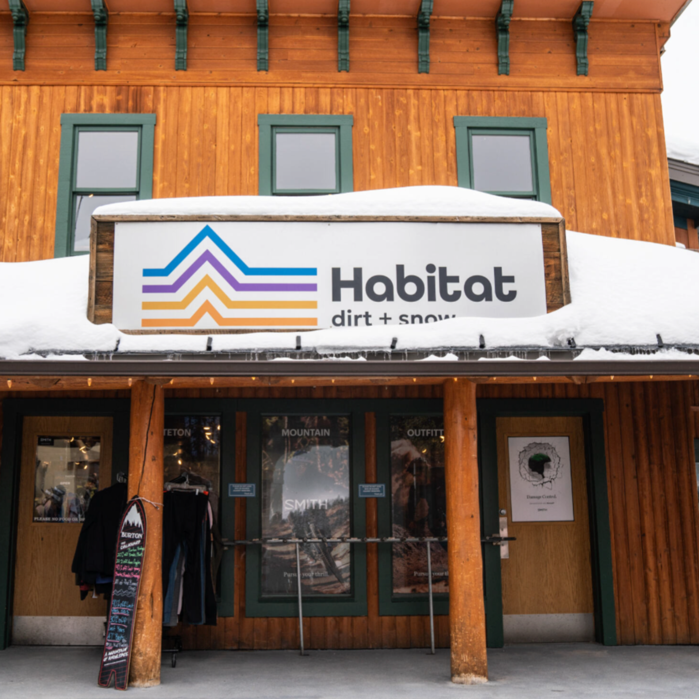 Snow-covered wooden storefront with "Habitat" sign above the entrance.