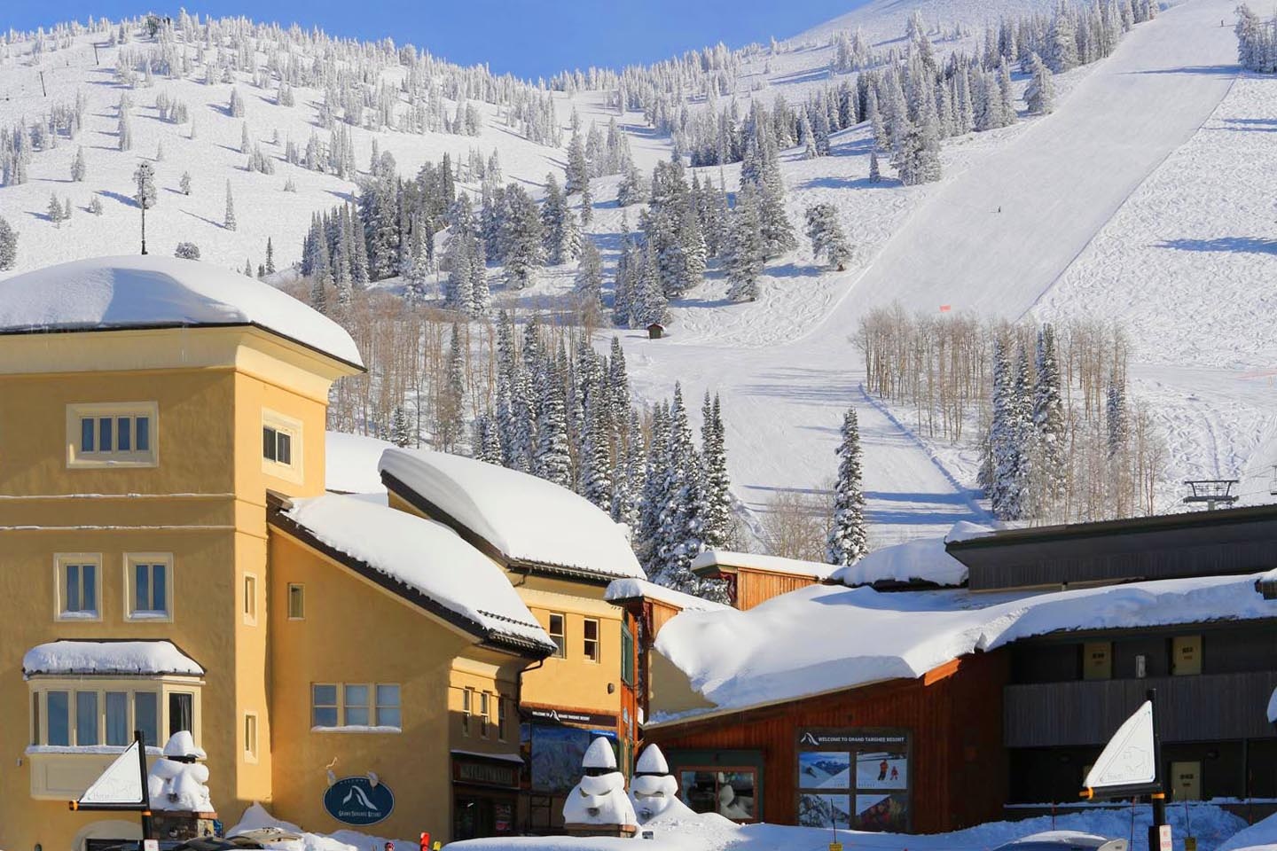 Snowy ski resort buildings under a clear blue sky.