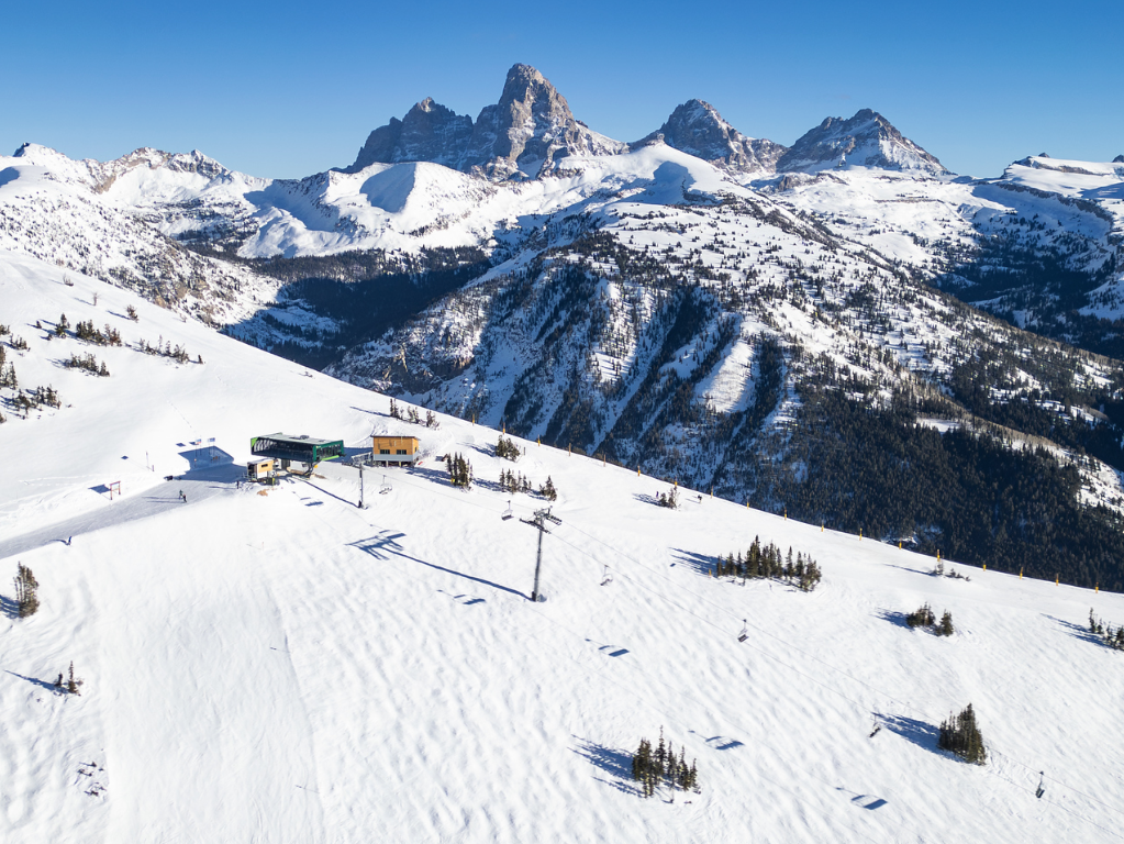 Snowy mountain landscape with ski lift and clear blue sky.