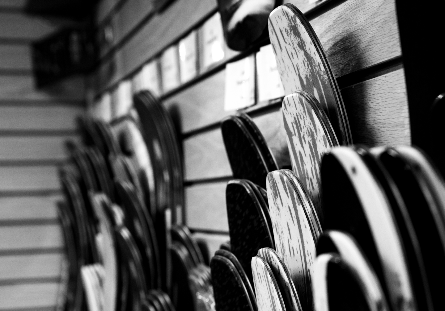 Black and white photo of skateboards lined on a wall display.