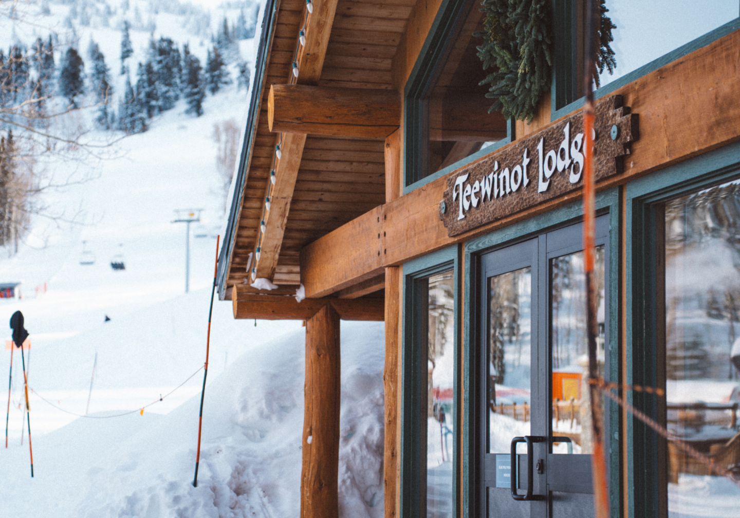Snowy lodge exterior with mountains in the background.