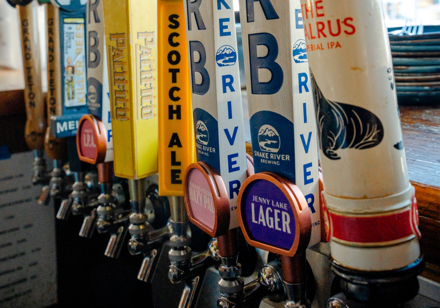 Beer taps in a row at a bar, featuring various colorful handles.
