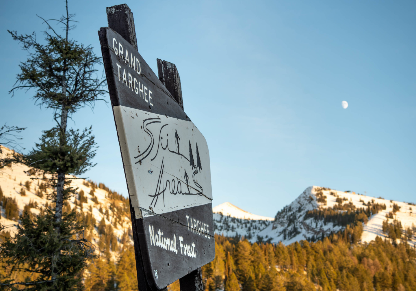 Sign at snowy mountain with blue sky and moon background.