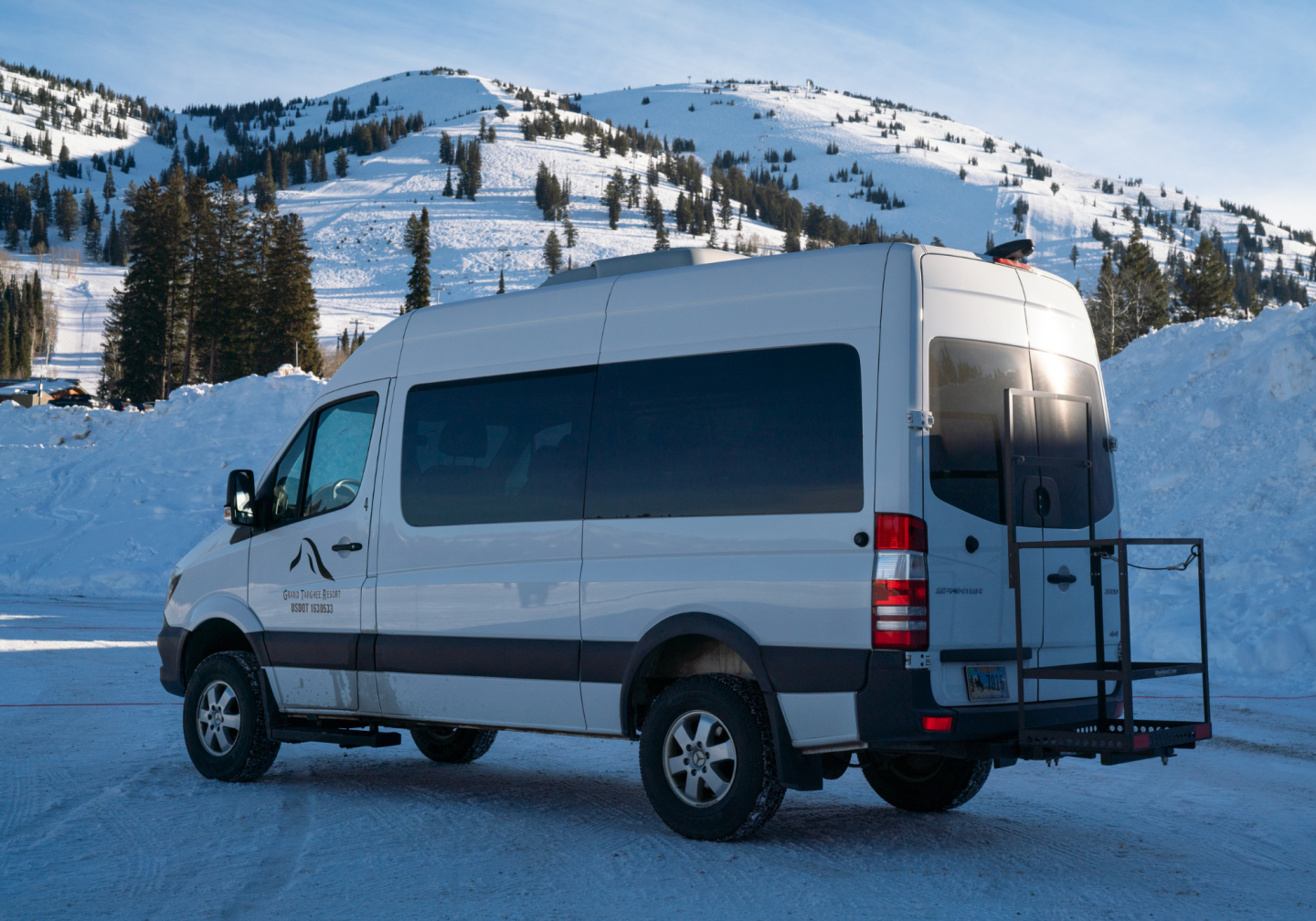 White van parked in snowy mountain landscape.