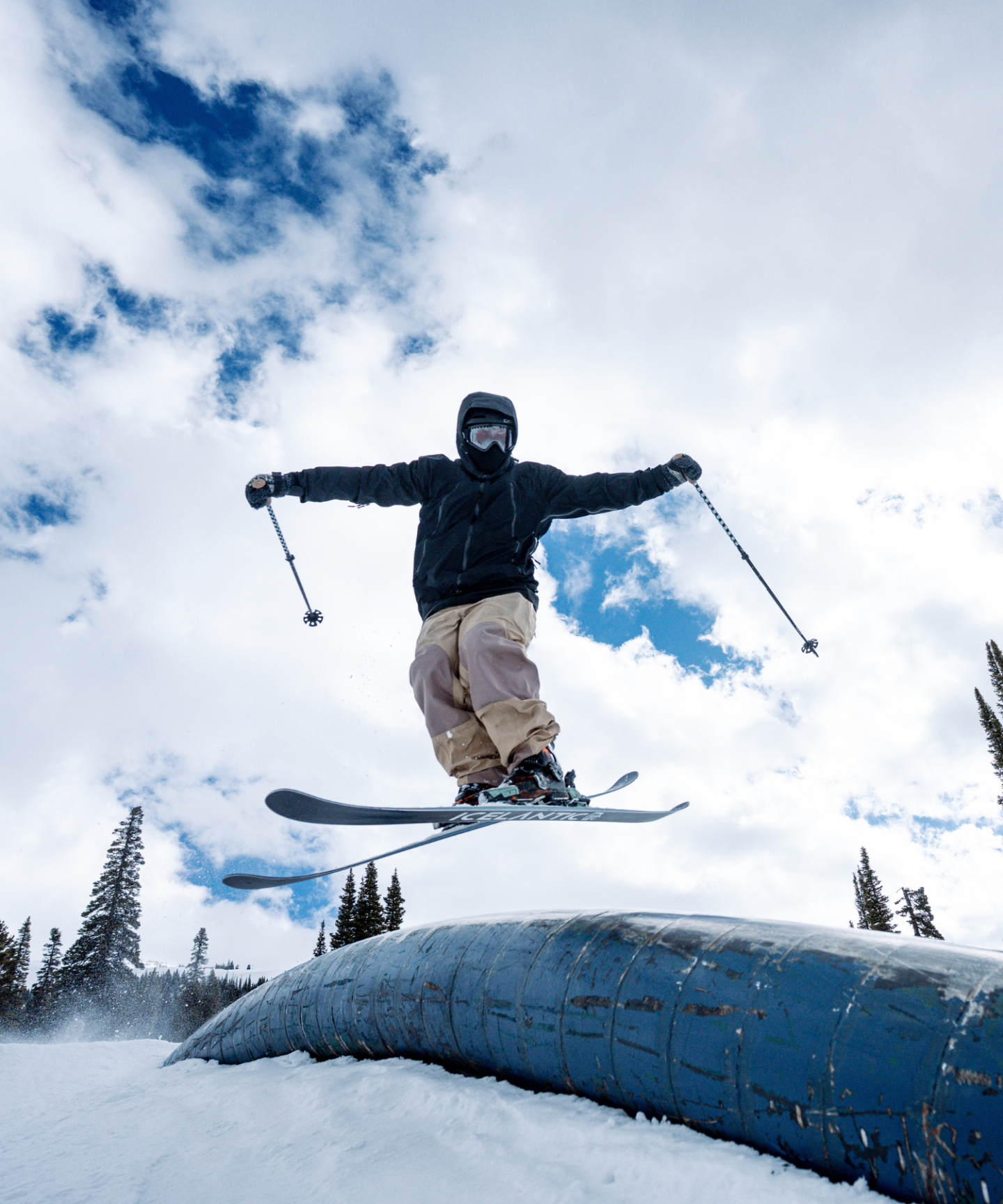 Skier in mid-air jumping over a snow-covered obstacle.