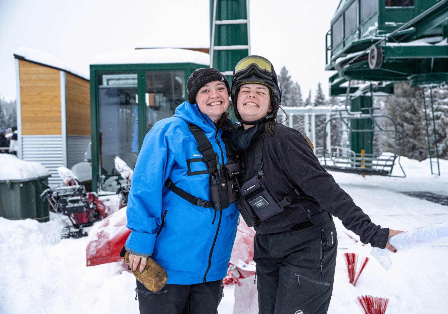 Two people smiling at a snowy ski resort.
