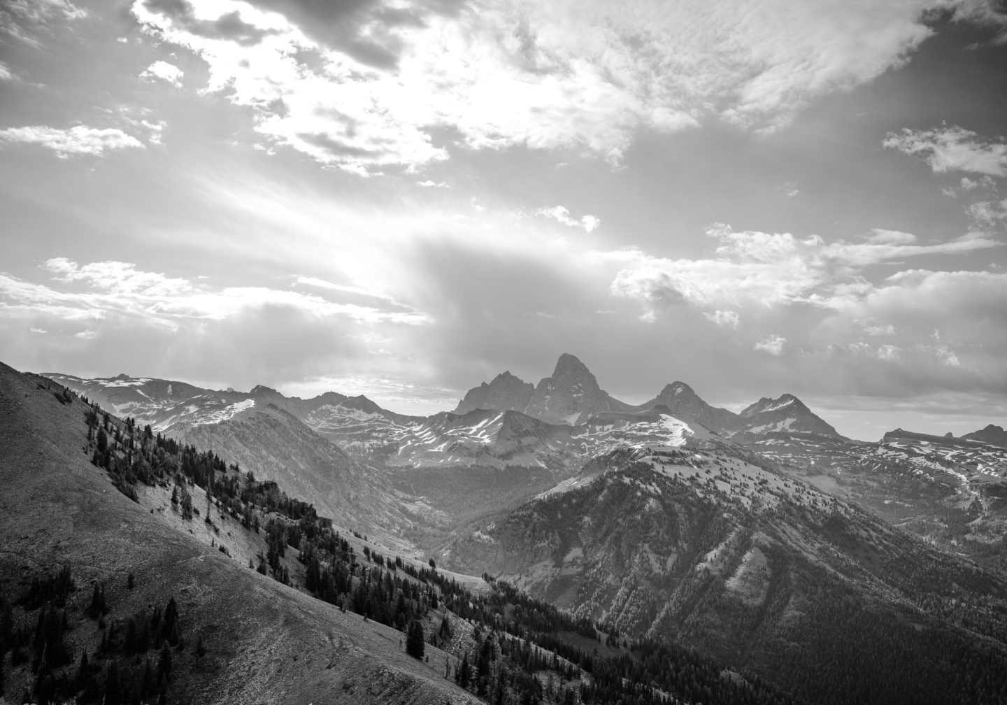 Black and white photo of mountain range under a cloudy sky.