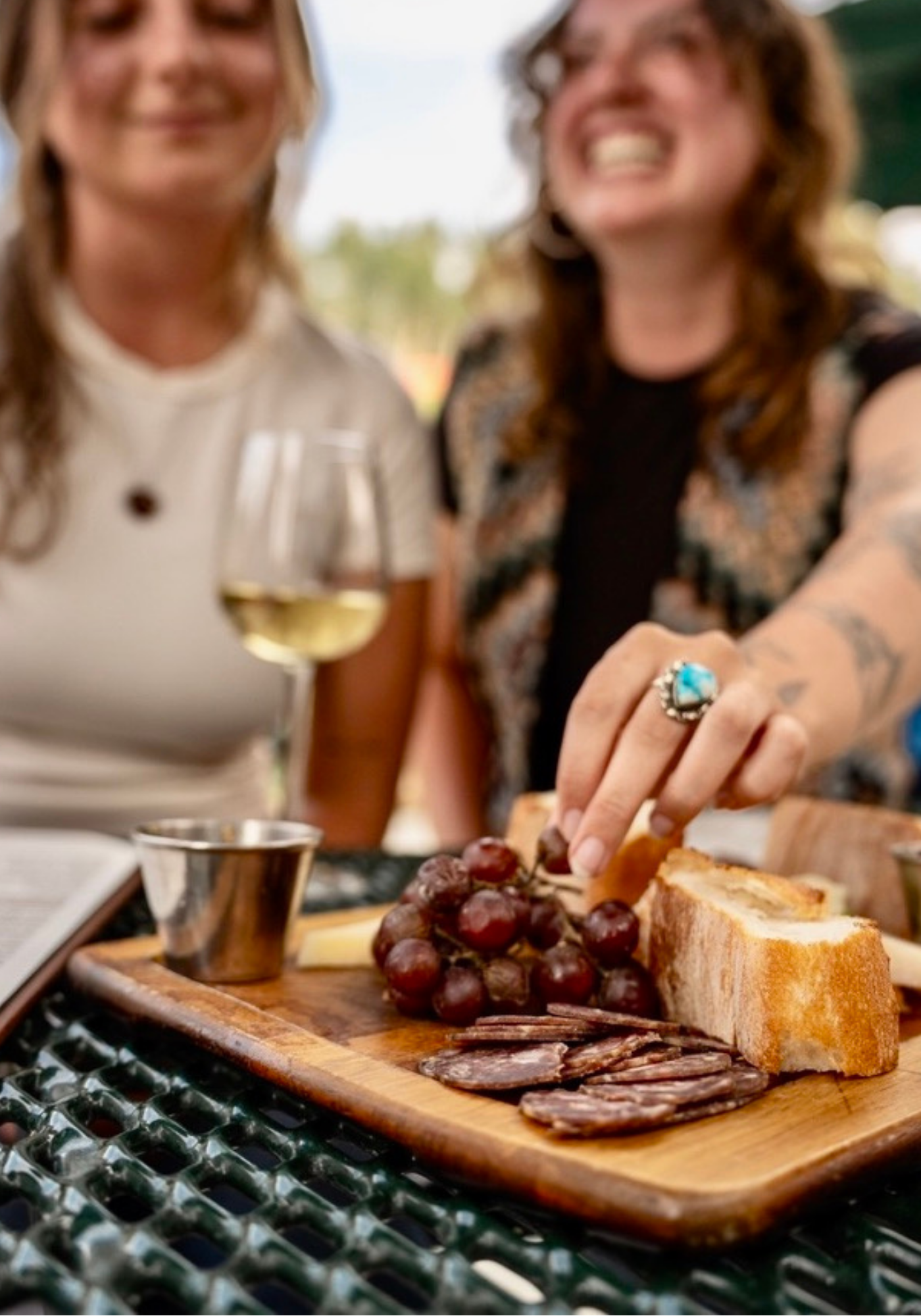 Cheese and grape platter on a table with two people in the background.