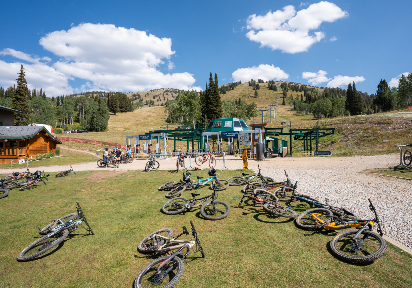 Mountain biking park with hills, bikes on grass, and chairlift under blue sky.