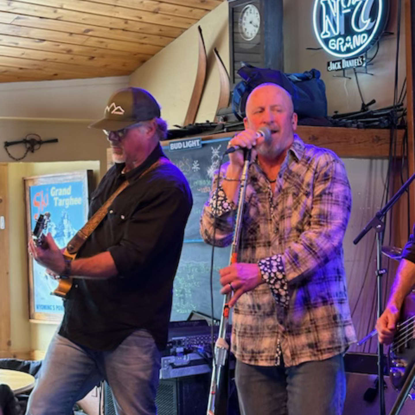 Singers performing on stage with guitars, under blue lighting.