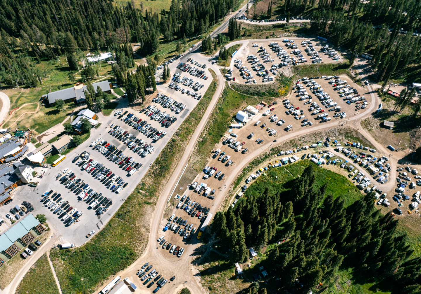 Aerial view of large forested parking lot filled with cars.