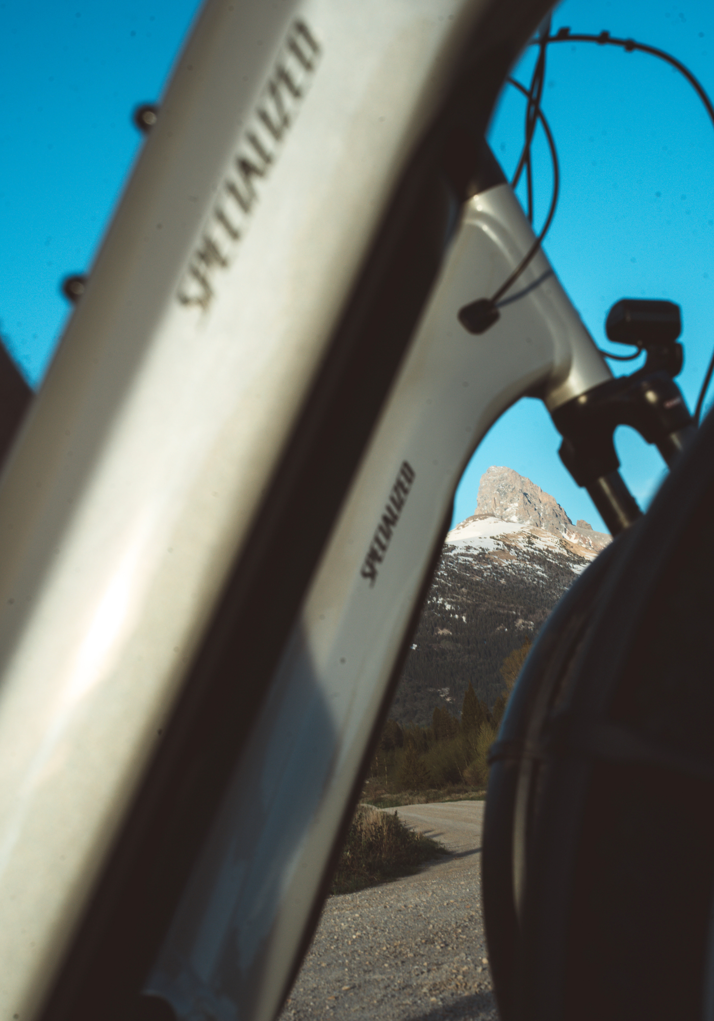 Bicycle frame with mountain peak in background, under clear blue sky.