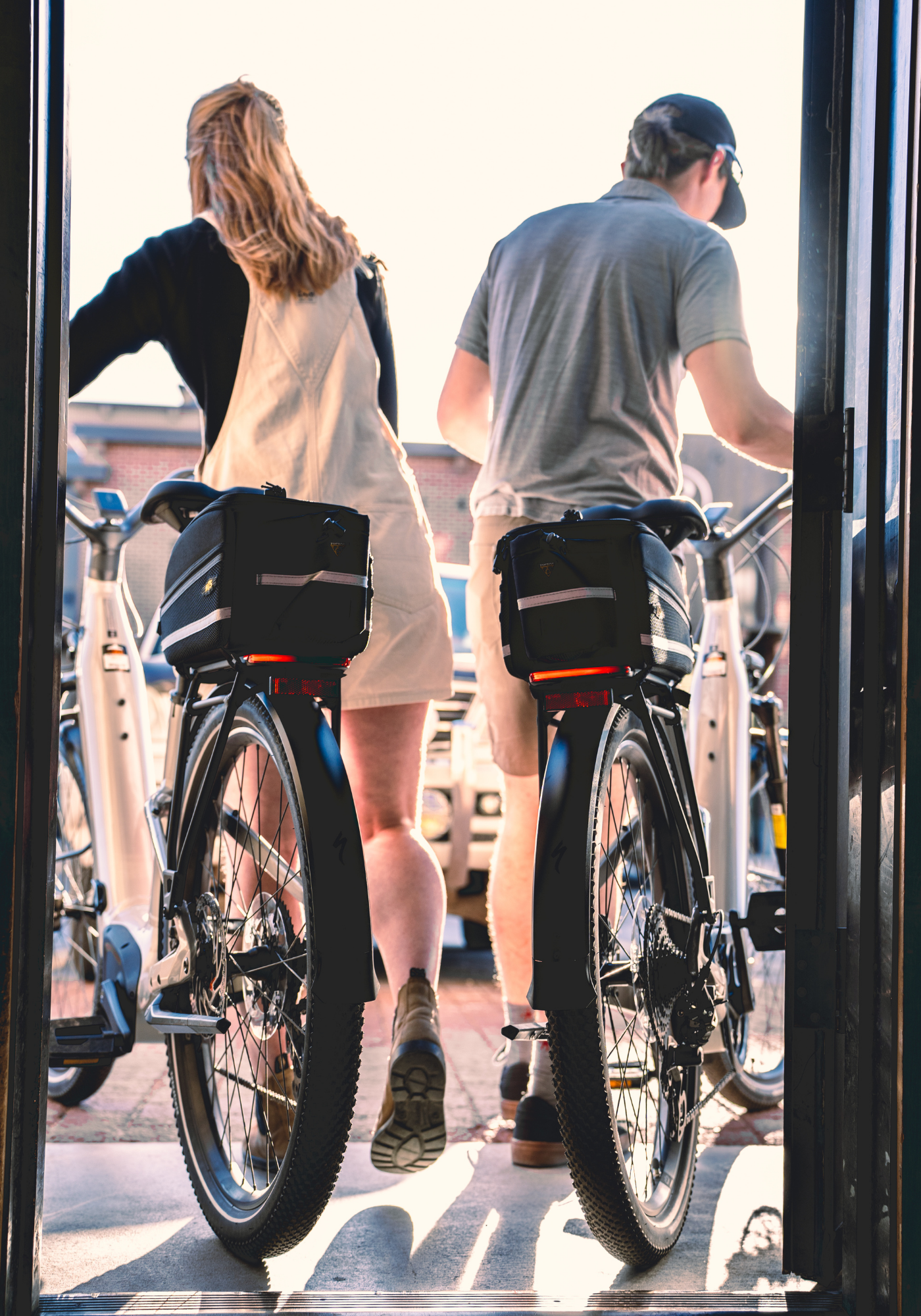 Two people exit through double doors with bicycles.