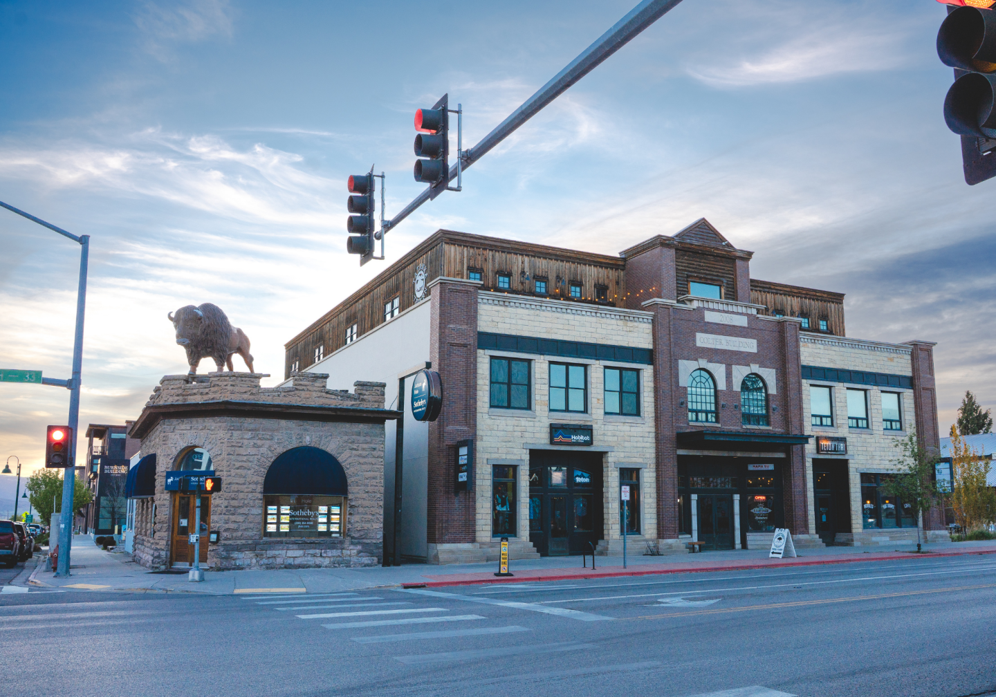 Street corner with a brick building and a bison statue on the roof.
