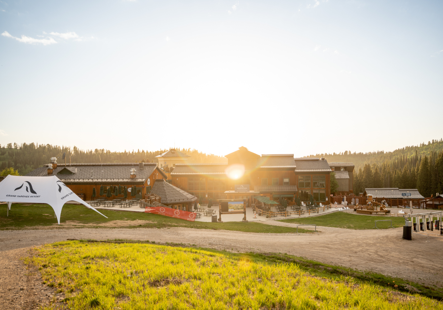 Large wooden lodge at sunset, surrounded by trees and grass.