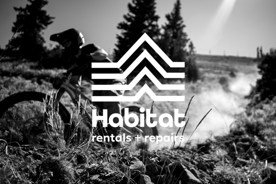 Cyclist on rocky trail in forest with "Habitat" logo overlay.