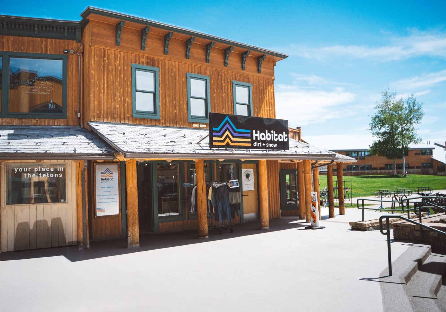 Wooden building with a store sign, under a clear blue sky.